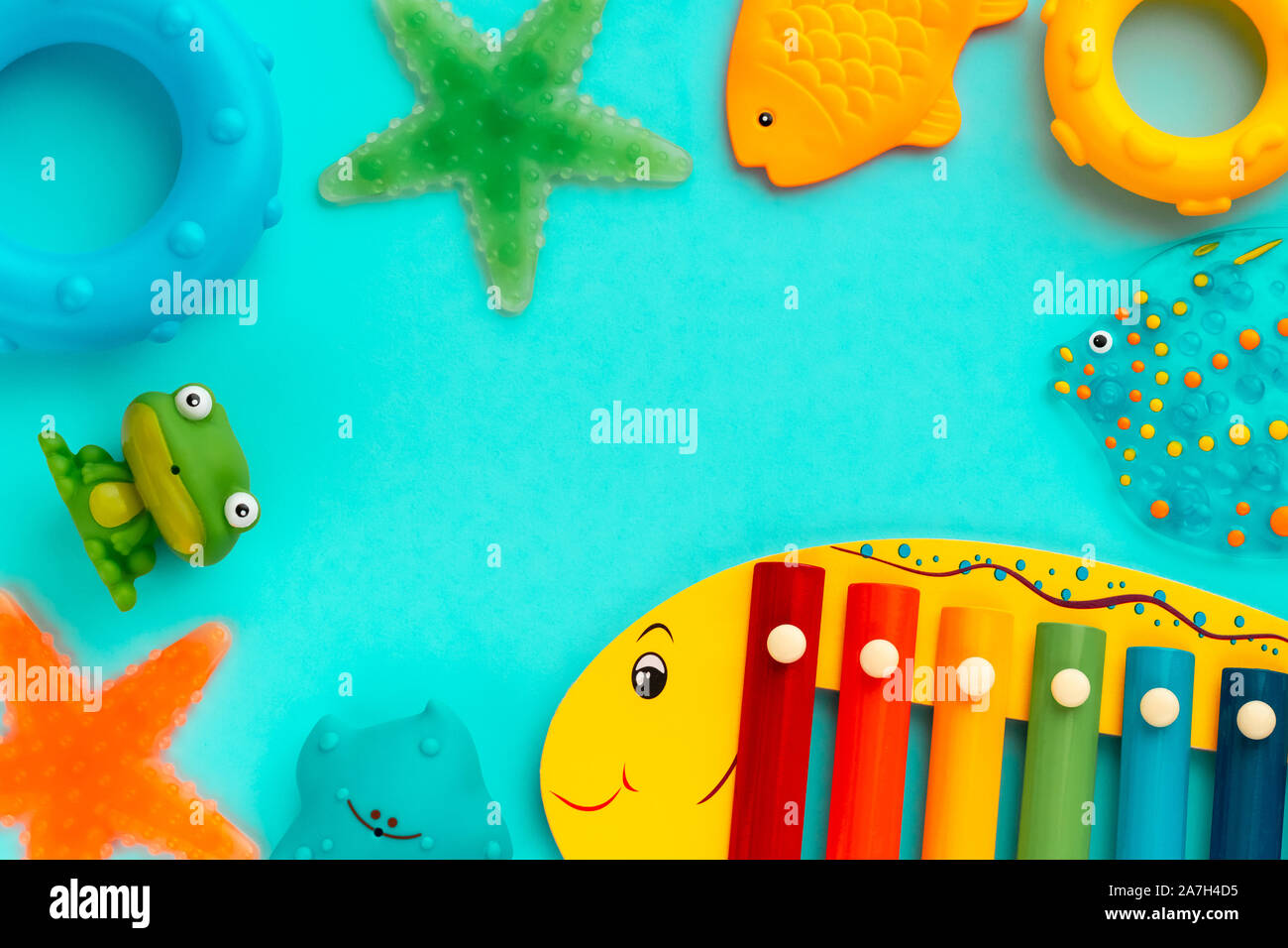 Top view on children's educational and music games, frame from multicolored  kids toys on light blue paper background. Circles, fish, frog, starfish,  xylophone. Sea, ocean concept. Flat lay, copy space for text