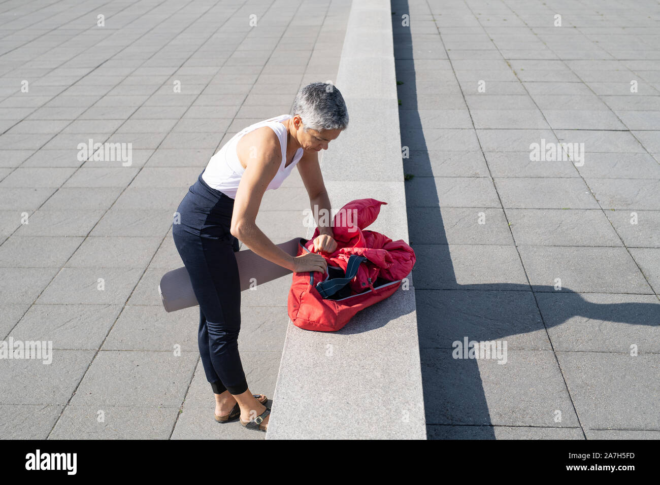 Middle-aged woman packing up yoga gear by ocean Stock Photo