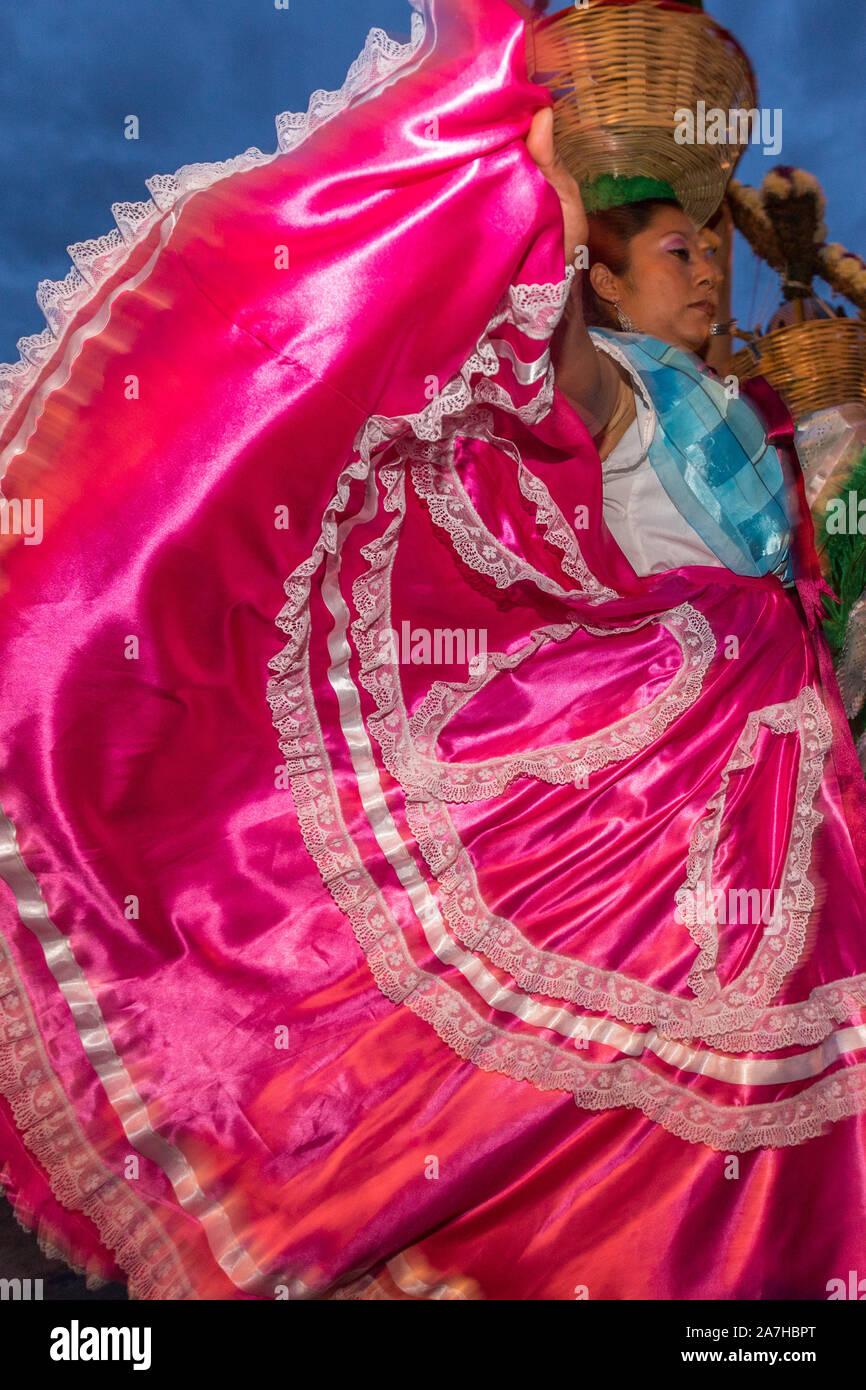 Young women dressed in traditional costumes perform the Flor de Pina dance in a comparsas past the Santo Domingo de Guzmán Church during the Day of the Dead Festival known in Spanish as Día de Muertos on November 2, 2013 in Oaxaca, Mexico. Stock Photo