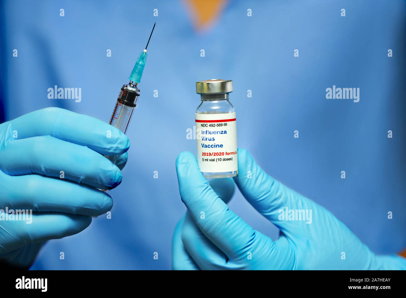Doctor holds 2019-2020 facimile influenza virus vaccine and syringe in gloved hands. Stock Photo