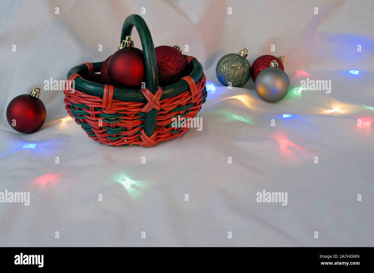 Christmas basket with tree ornaments and lights on a white background