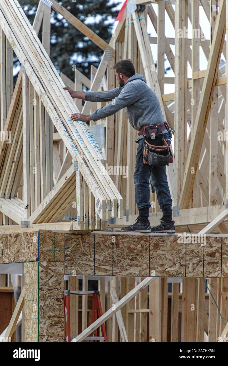 Housing construction workers installing roof trusses on a new home Stock Photo