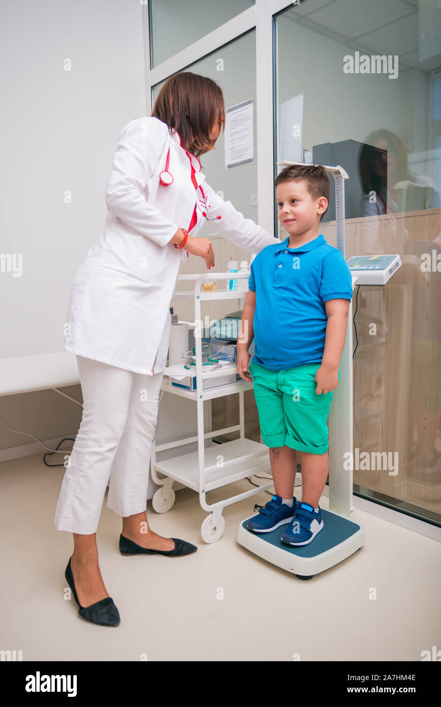 Female doctor measuring the height of little boy in a clinic ( hospital