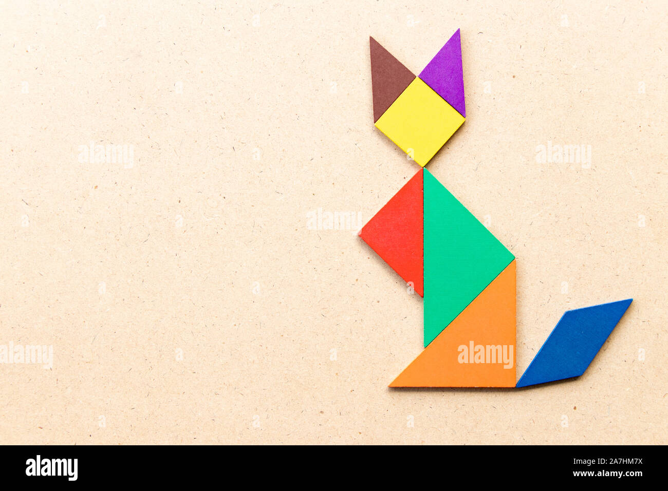 Color tangram puzzle in sitting cat shape on wood background Stock