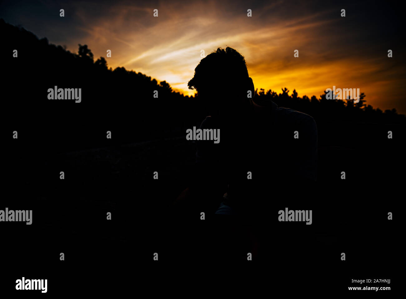 Silhouette man sitting on bench against sunset sky Stock Photo - Alamy