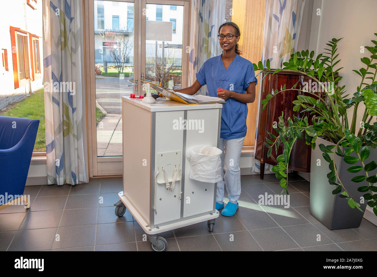 Female nurse handing out medicine from a medicine trolley. Stock Photo