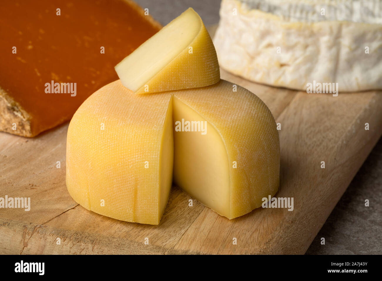 Diversity of traditional French cheese like Camembert, Mimolette on a cutting board and Le Mouillotin close up Stock Photo