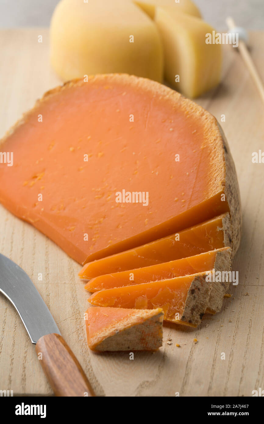 French Mimolette cheese cut into pieces on a cutting board Stock Photo