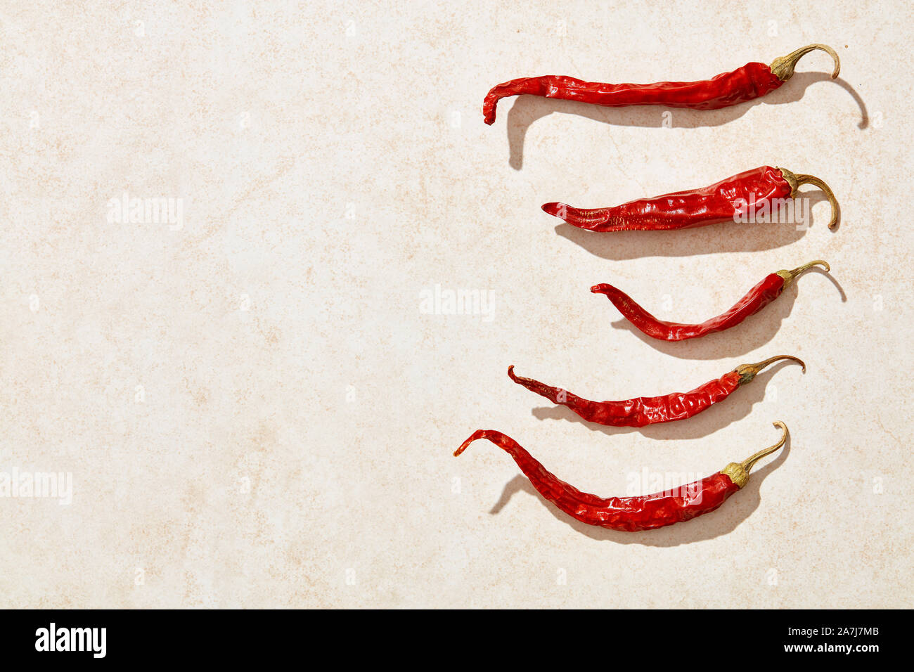 Sun dried red hot chili peppers under harsh sunlight on stone background. Overhead view Stock Photo