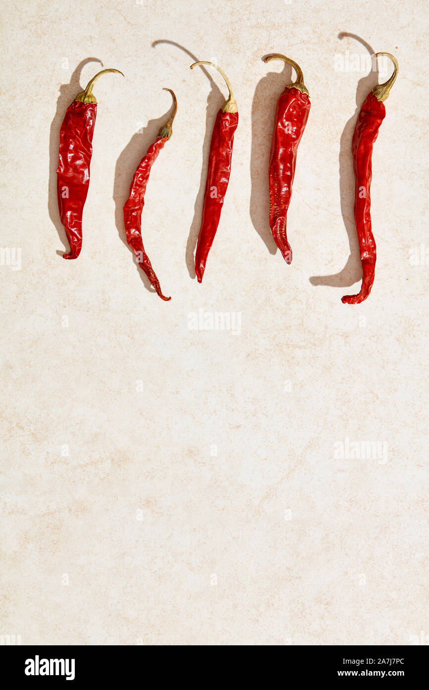 Sun dried red hot chili peppers under harsh sunlight on stone background. Overhead view Stock Photo