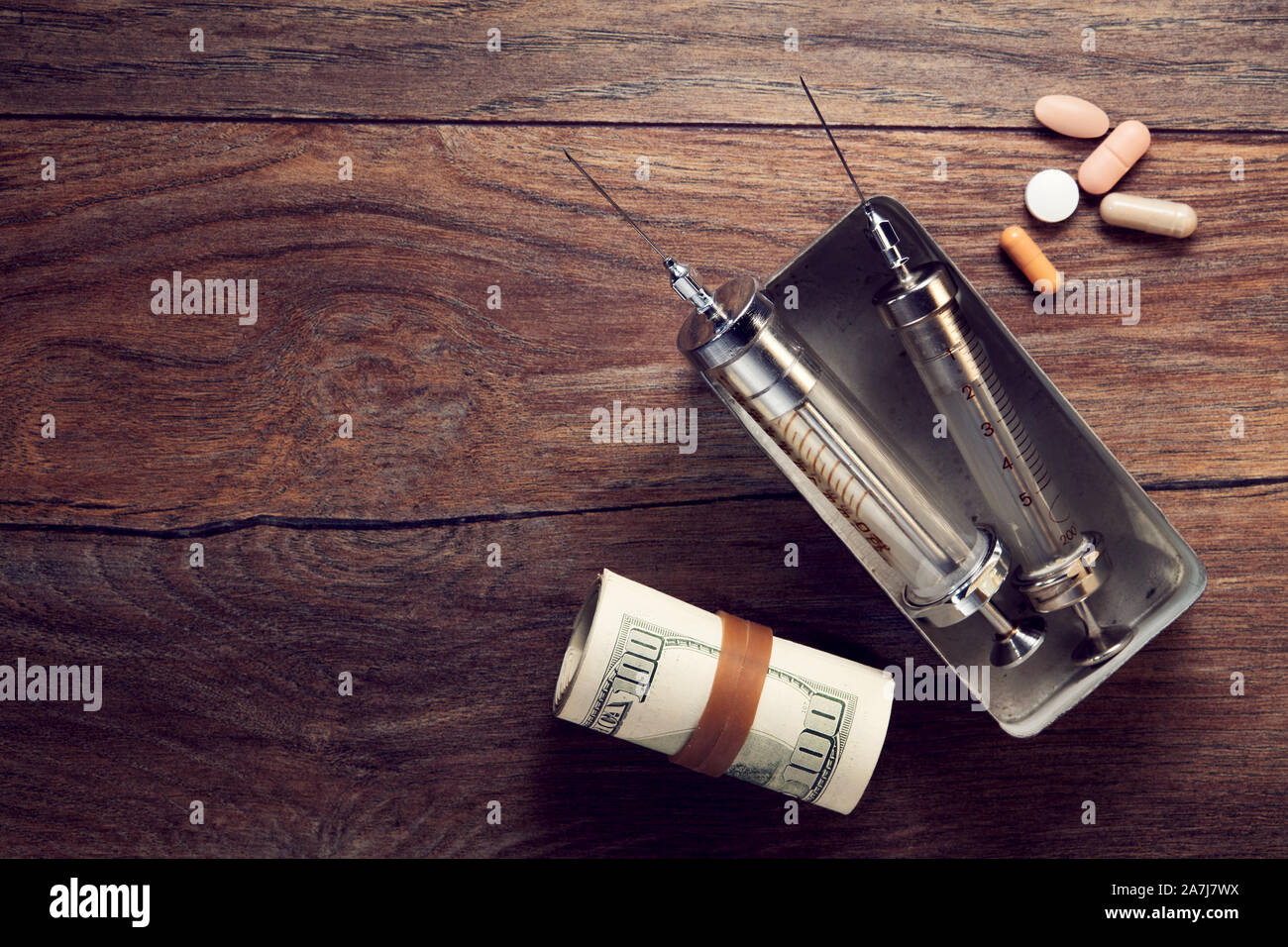 Vintage syringes, medical pills and rolled dollar bills on wooden table