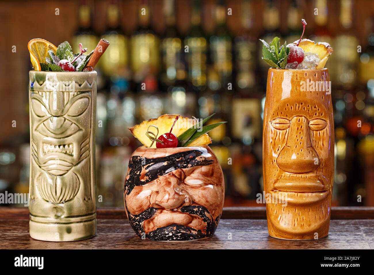 Set of three tropical cocktails in tiki glasses in a nightclub on the  background of a bar counter. Long alcoholic cocktails with ice, rum and  various Stock Photo - Alamy