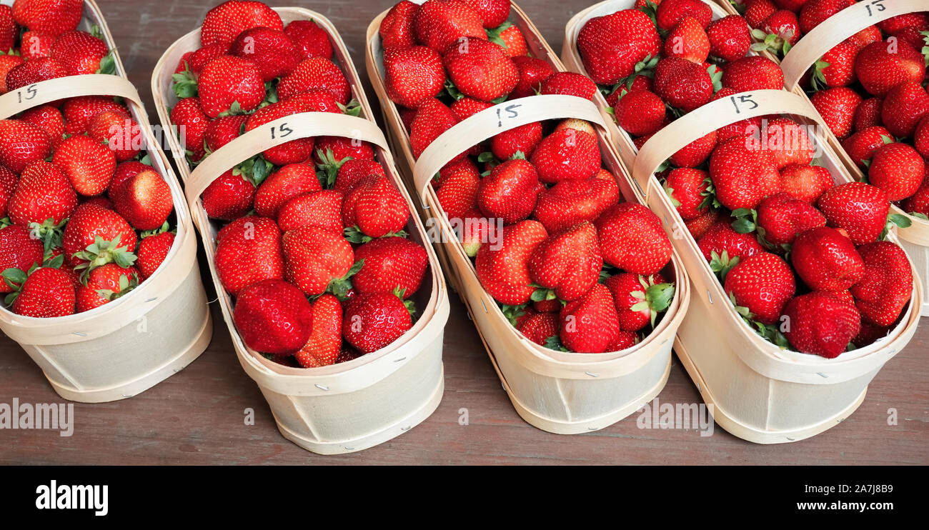 Fresh strawberries in the basket on the wooden stall of a farmer's ...