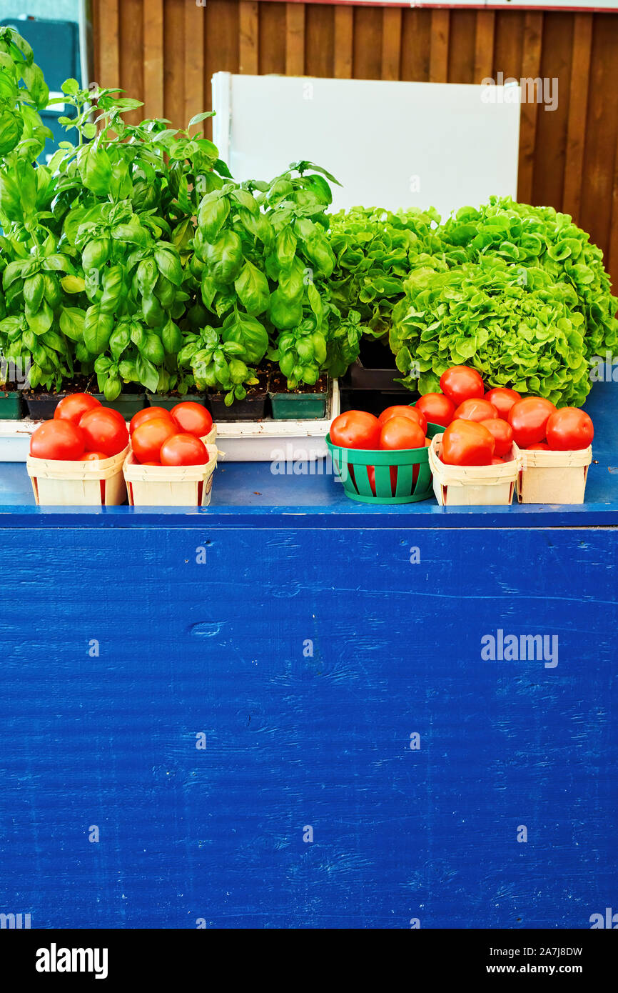 Fresh leafy green vegetables and tomatoes in baskets on the farmers ...