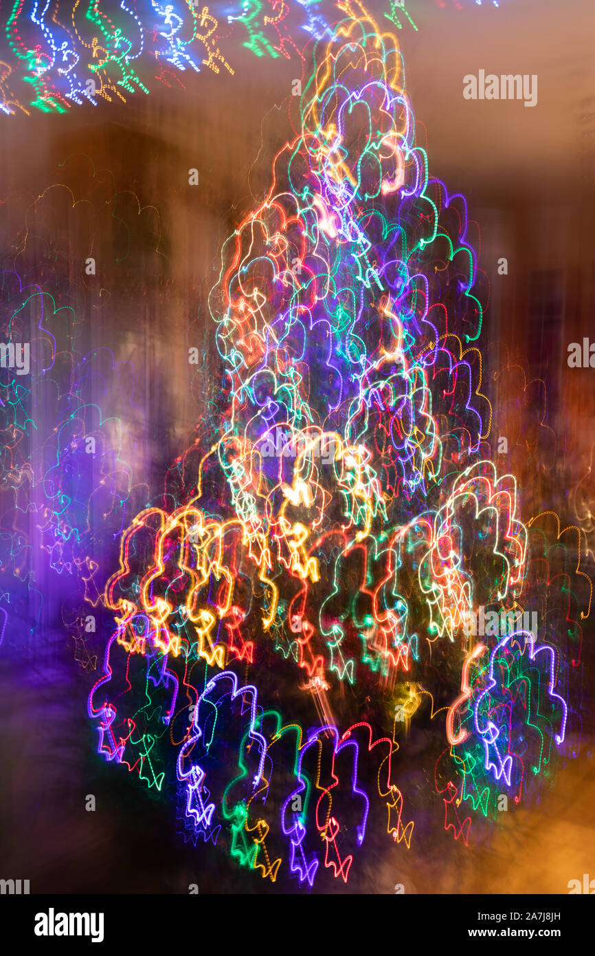 Abstract christmas neon background. Fancy Christmas tree with blurred vertical hanging glowing garlands.  Photographic effect of long exposure while m Stock Photo