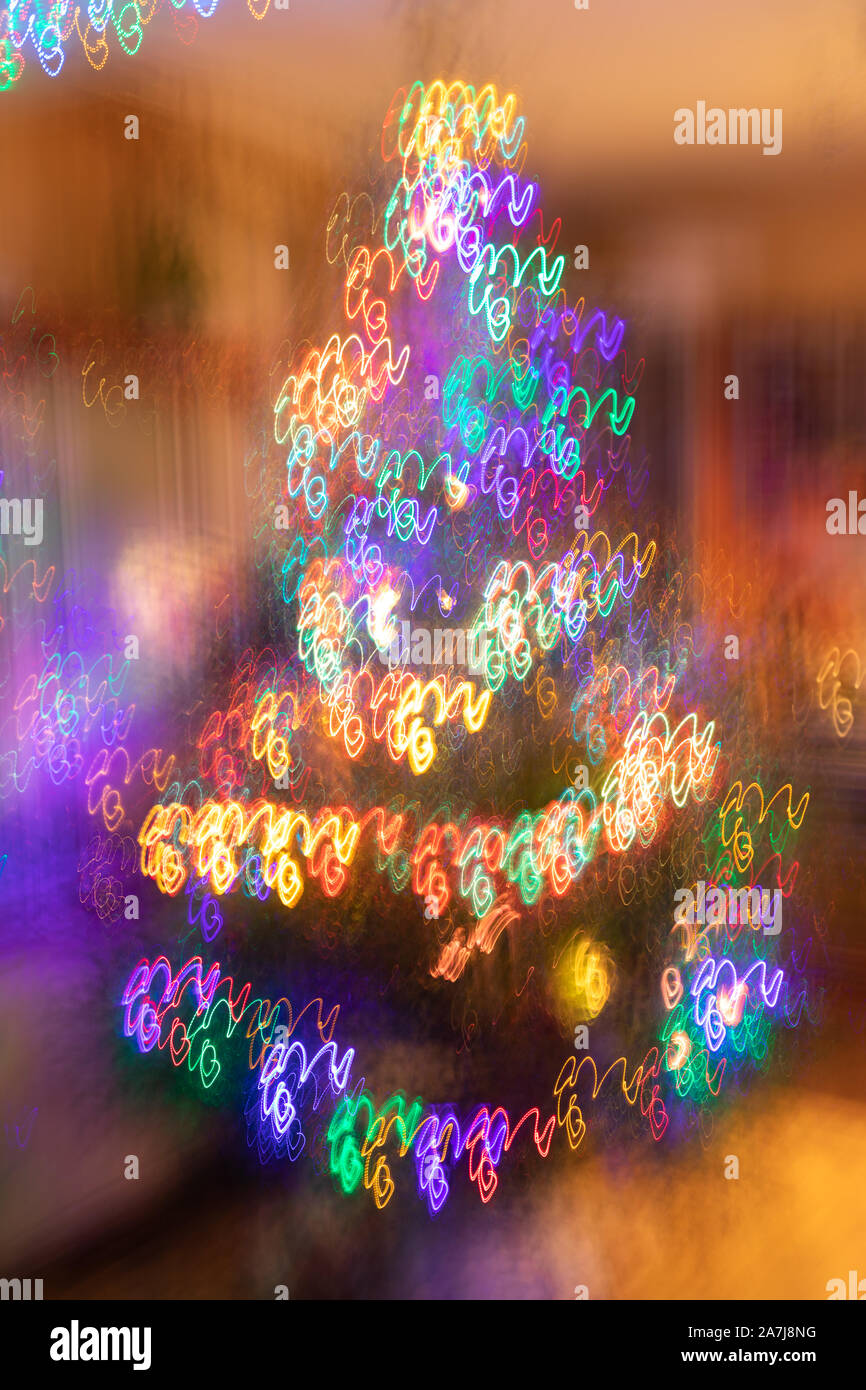 Abstract christmas background with fantasy Christmas tree with blurred glowing neon spiral garlands. Photographic effect of long exposure while moving Stock Photo