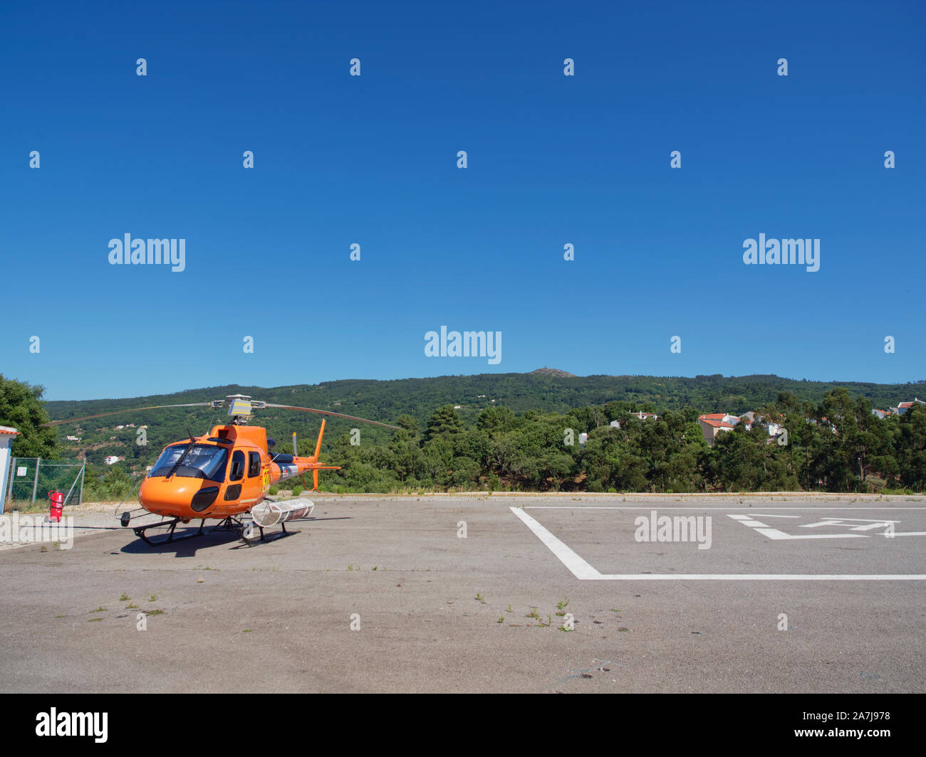 An orange Portuguese Rescue Helicopter of the Protecao Civil on its helipad in the mountain village of Monchique near the Algarve. Stock Photo