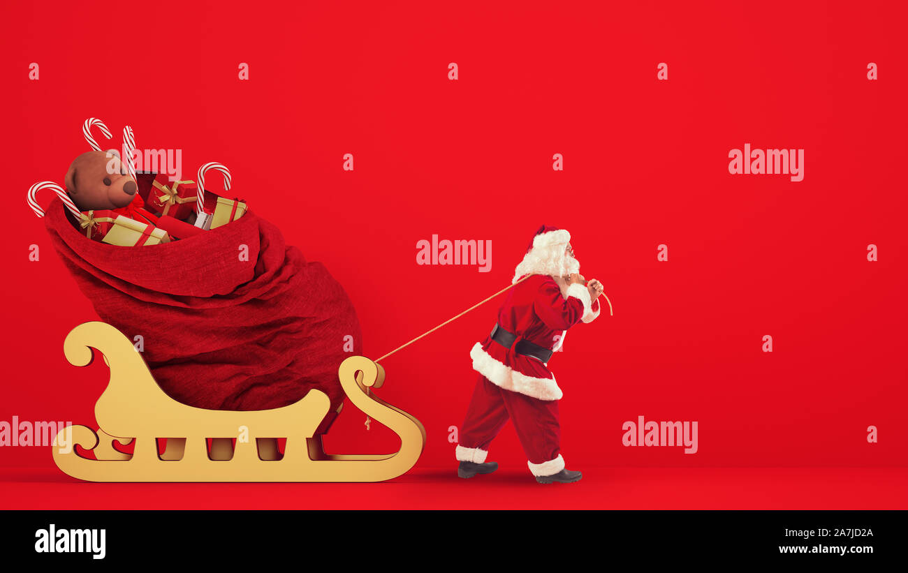 Santa Claus drags a large sack full of gifts with a golden sleigh on a red background Stock Photo