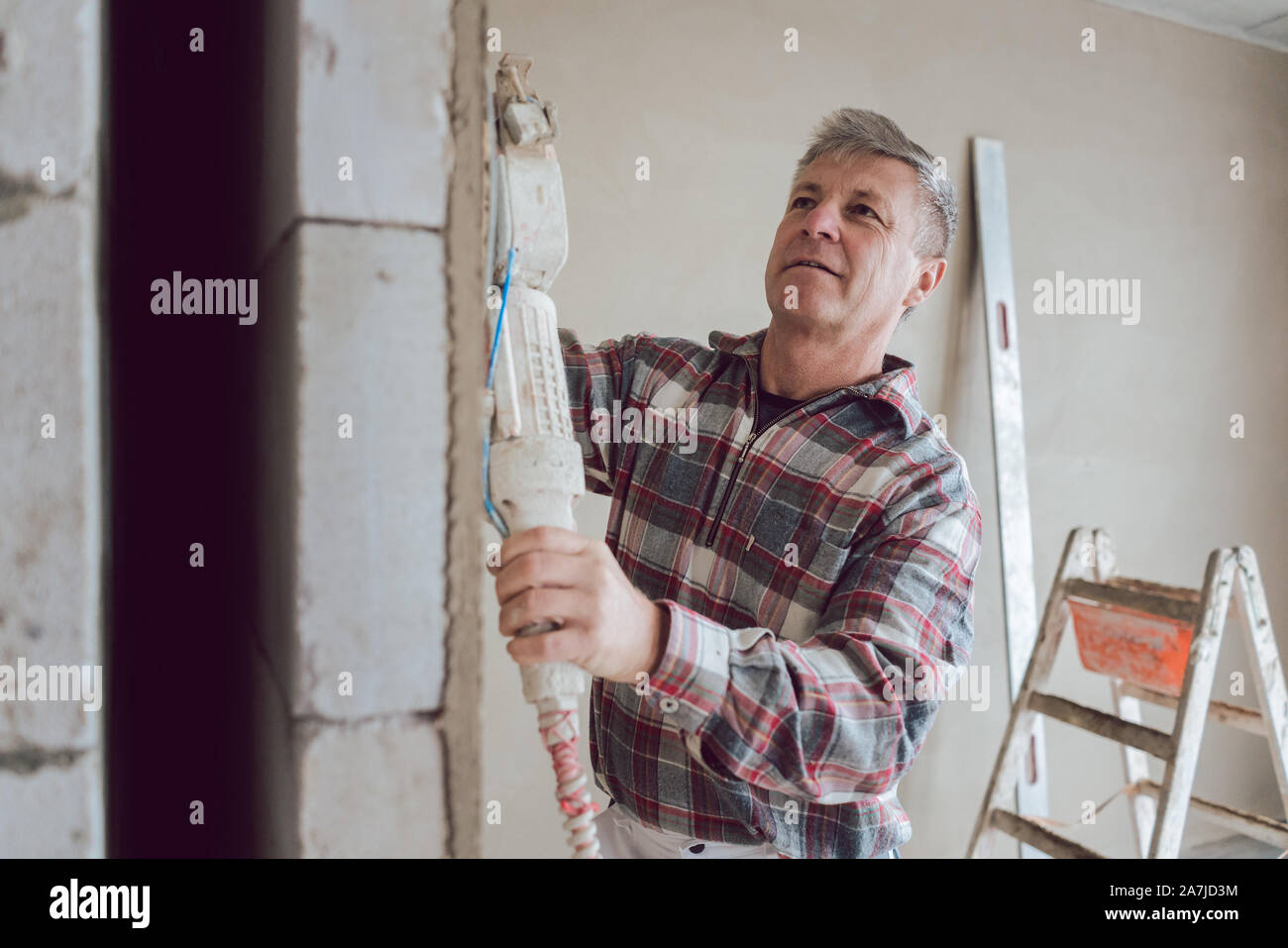 Plasterer smoothing interior wall with machine Stock Photo