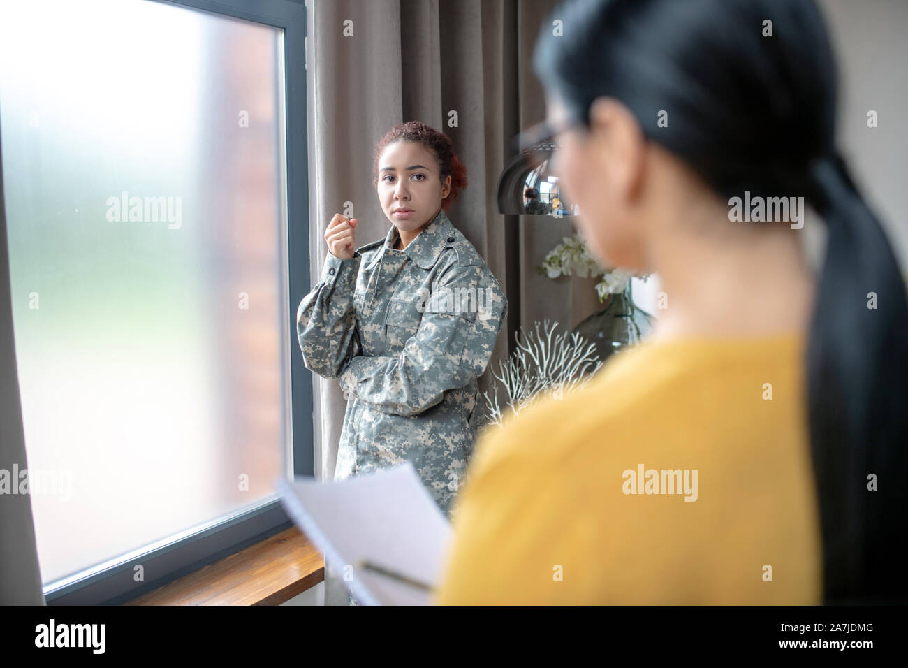 Stresse young servicewoman talking to her psychologist Stock Photo