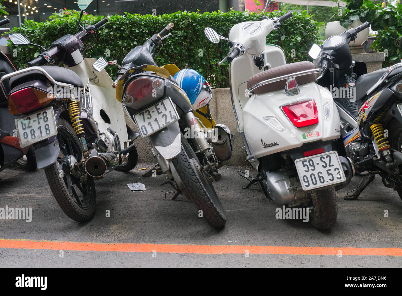 Horizontal image of parked scooters from behind showing license plates, taillights and worn tires. Stock Photo