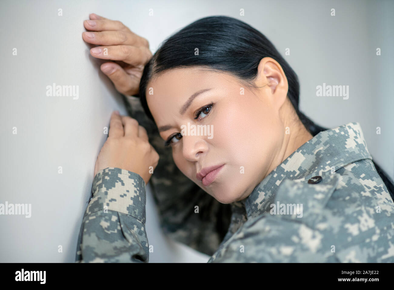 Dark-eyed Asian servicewoman feeling stressed and depressed Stock Photo