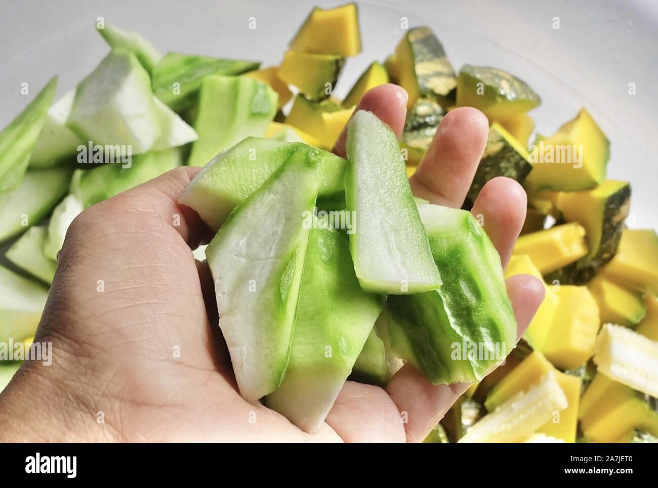 Vegetable, Hand Holding Raw Chopped Pumpkins, Angled Gourds or Sponge Gourds and Baby Corns Preparing for Cooking. Stock Photo