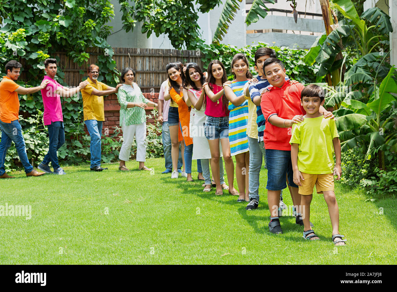 A group-of Three-generation Family walking in a line in-front of-their home in the gargen Stock Photo