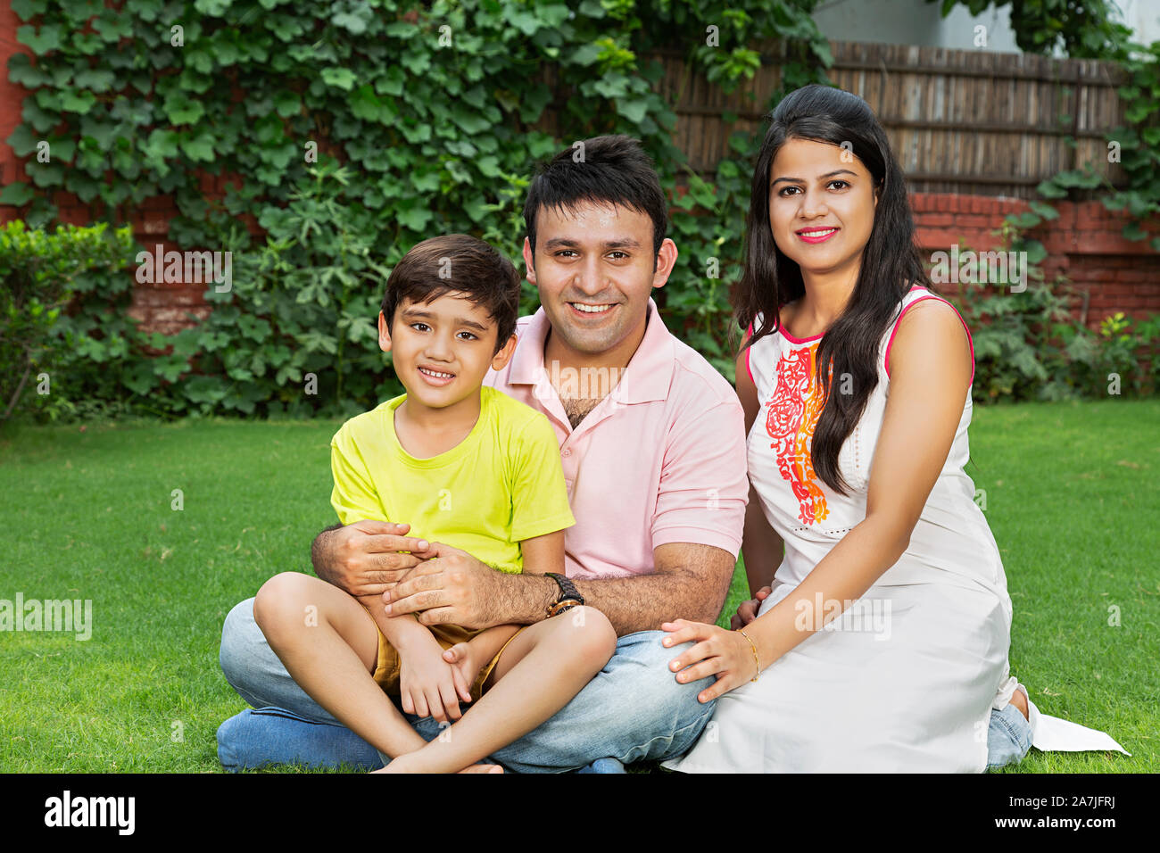 Happy Family Father And Mother With Little son Sitting on the grass and Relaxing At park Stock Photo