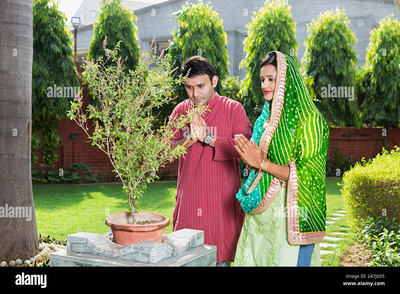 Indian Tradition married couple performing basil Tulsi Pooja in-courtyard of-their home Stock Photo