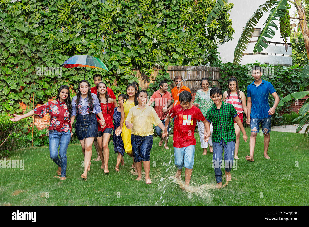 Group-of Big family Members holding hands Walking Together having Fun enjoy The Rain in-garden Of-Their home Stock Photo