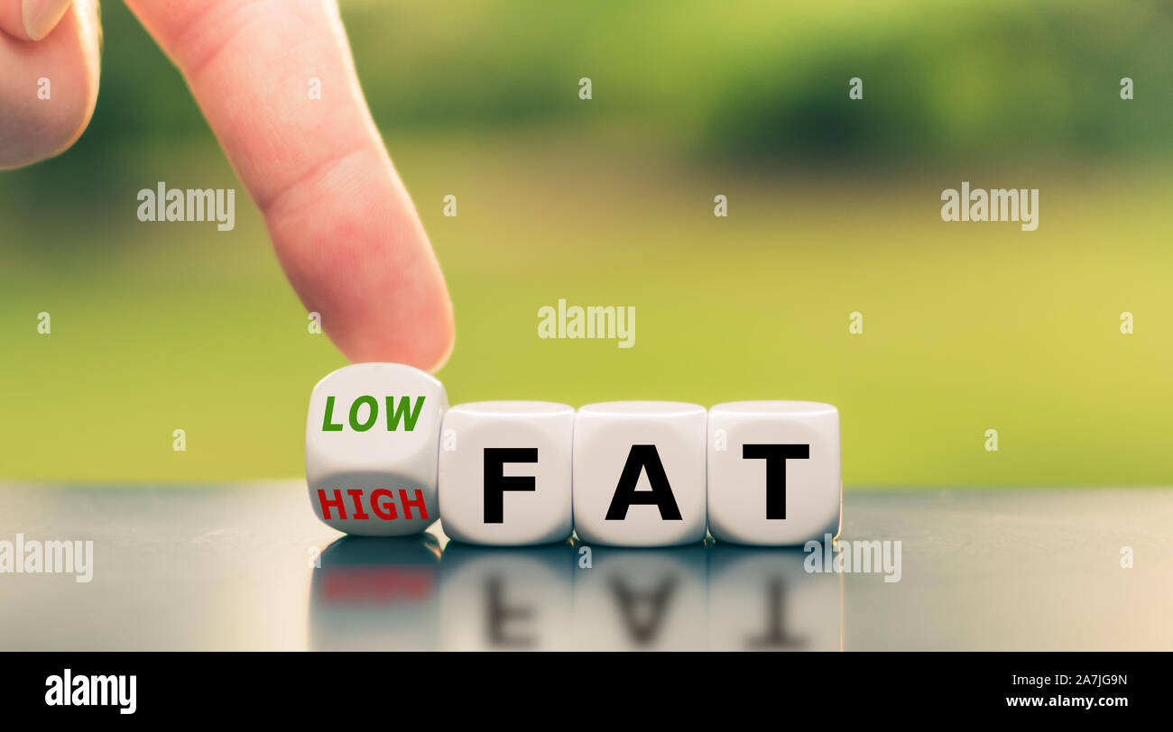 Hand turns a dice and changes the expression from 'high fat' to 'low fat'. Stock Photo