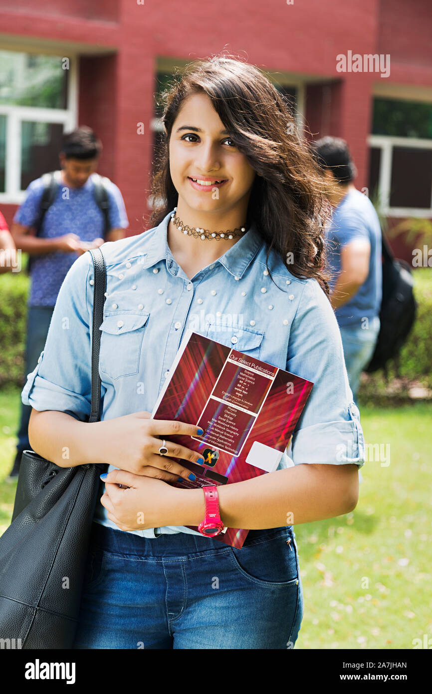 Young Girl College student Carrying Bag And Holding Book InOutside