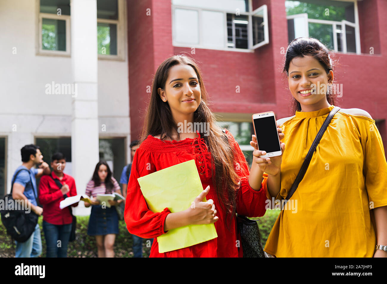 Two Young College Girls Student Friends toegther Showing mobile-Phone In-Outside University Campus Stock Photo