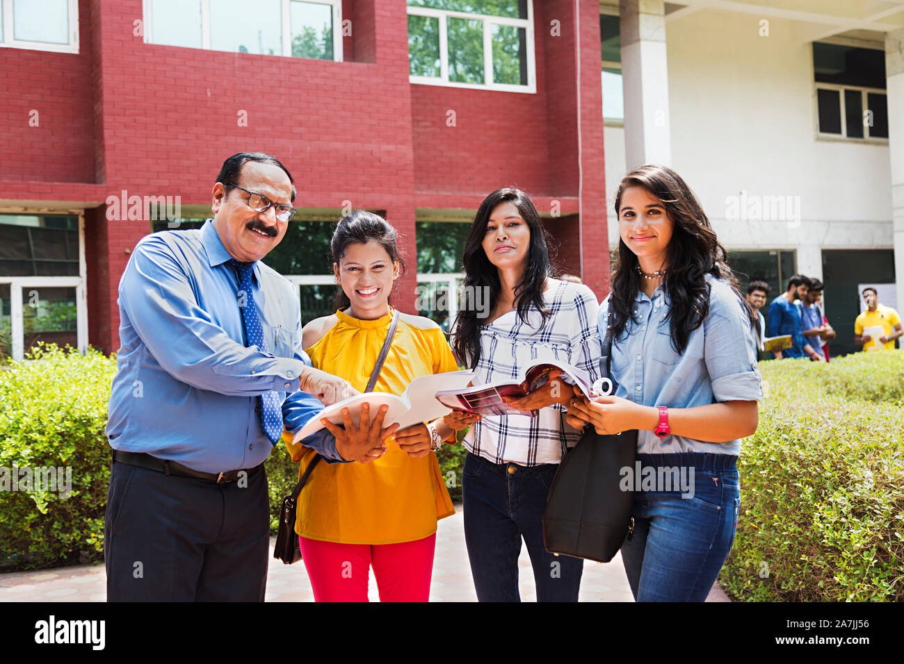 Three College Girls Students With Teacher studying Book Helping Support in-Outside Campus Building Stock Photo