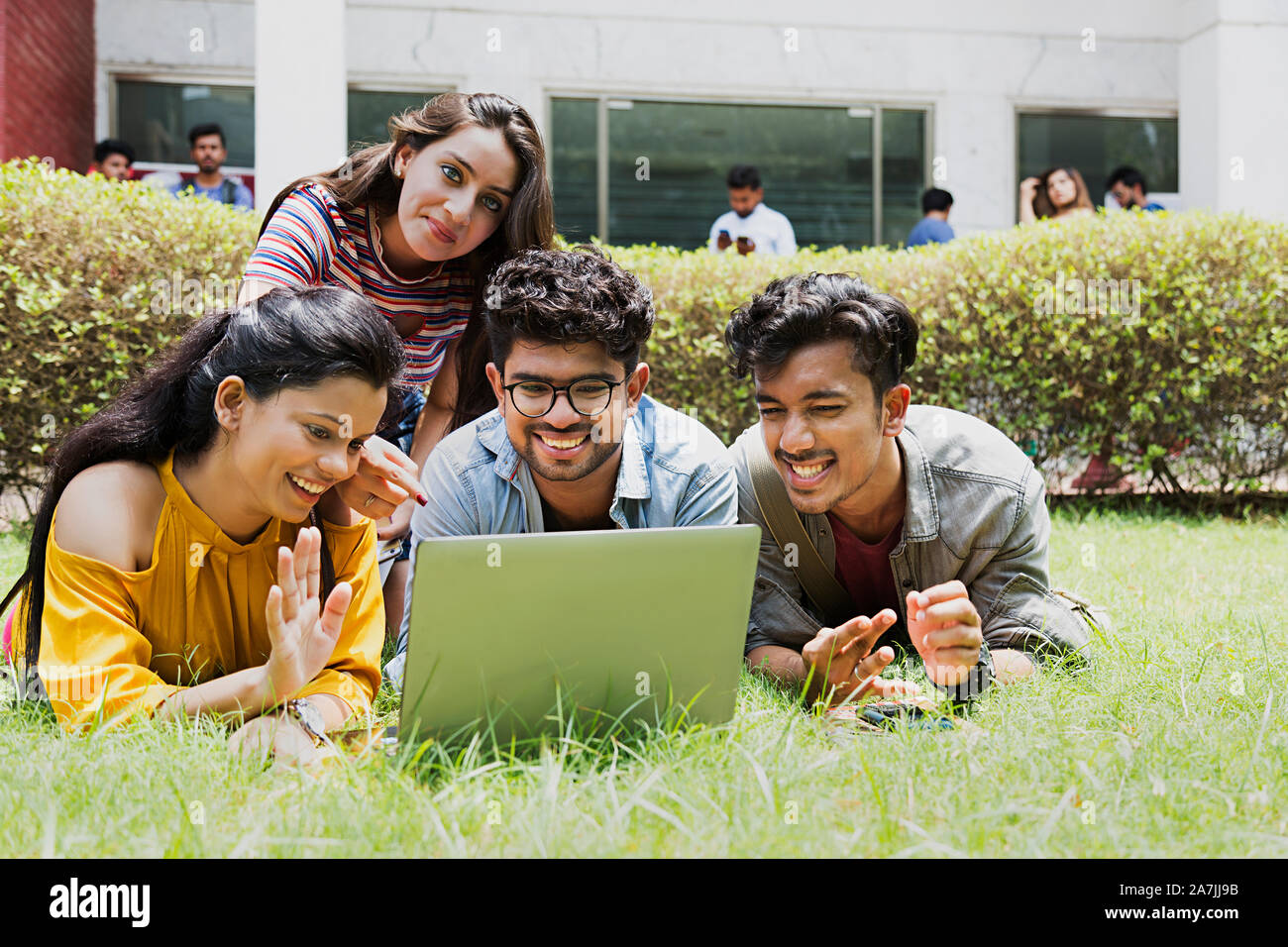 Four College Students Friends Together Looking-At laptop Screen Chatting In-Outside Campus Stock Photo