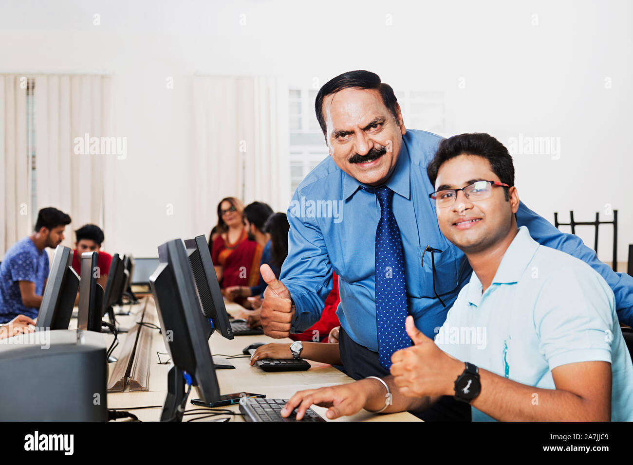 College Professor With Young-man Student Studying Computer And Showing Thumbs-up in Computer lab Stock Photo