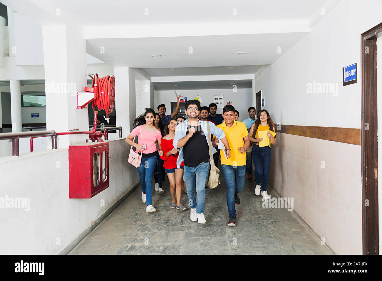 Group Of College Students Friends Running Fast Corridor Having Fun Cheerful At-Campus Stock Photo
