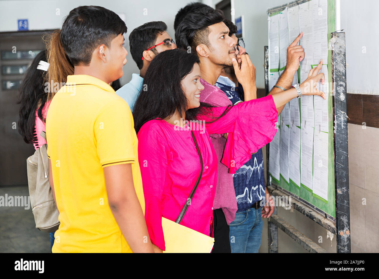 College Campus Boys And Girls Students Checking Exam result on Bulletin Board Stock Photo