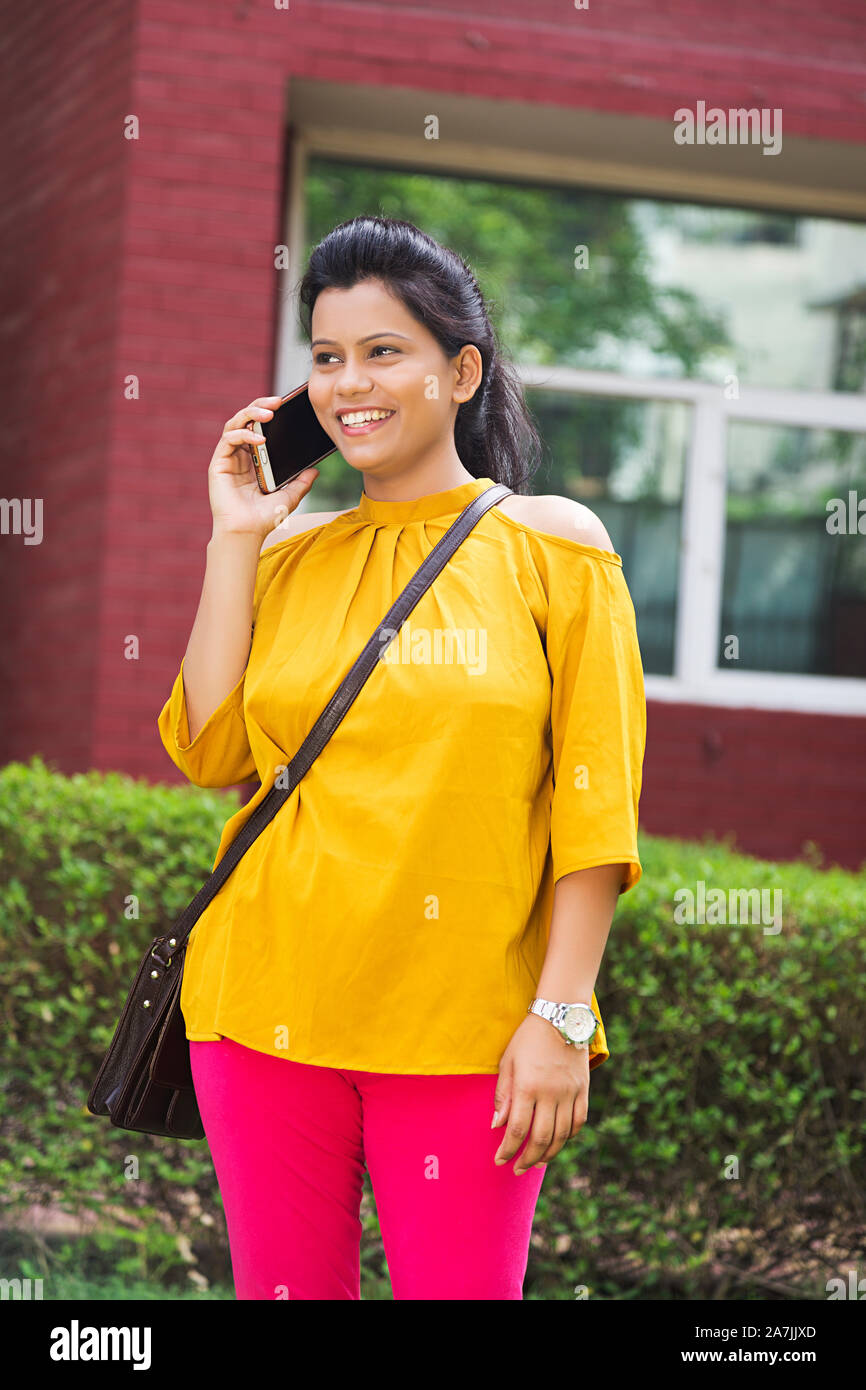 Happy Young Girl College Student Talking On mobile Phone Standing In-Outsidoors College Campus Stock Photo