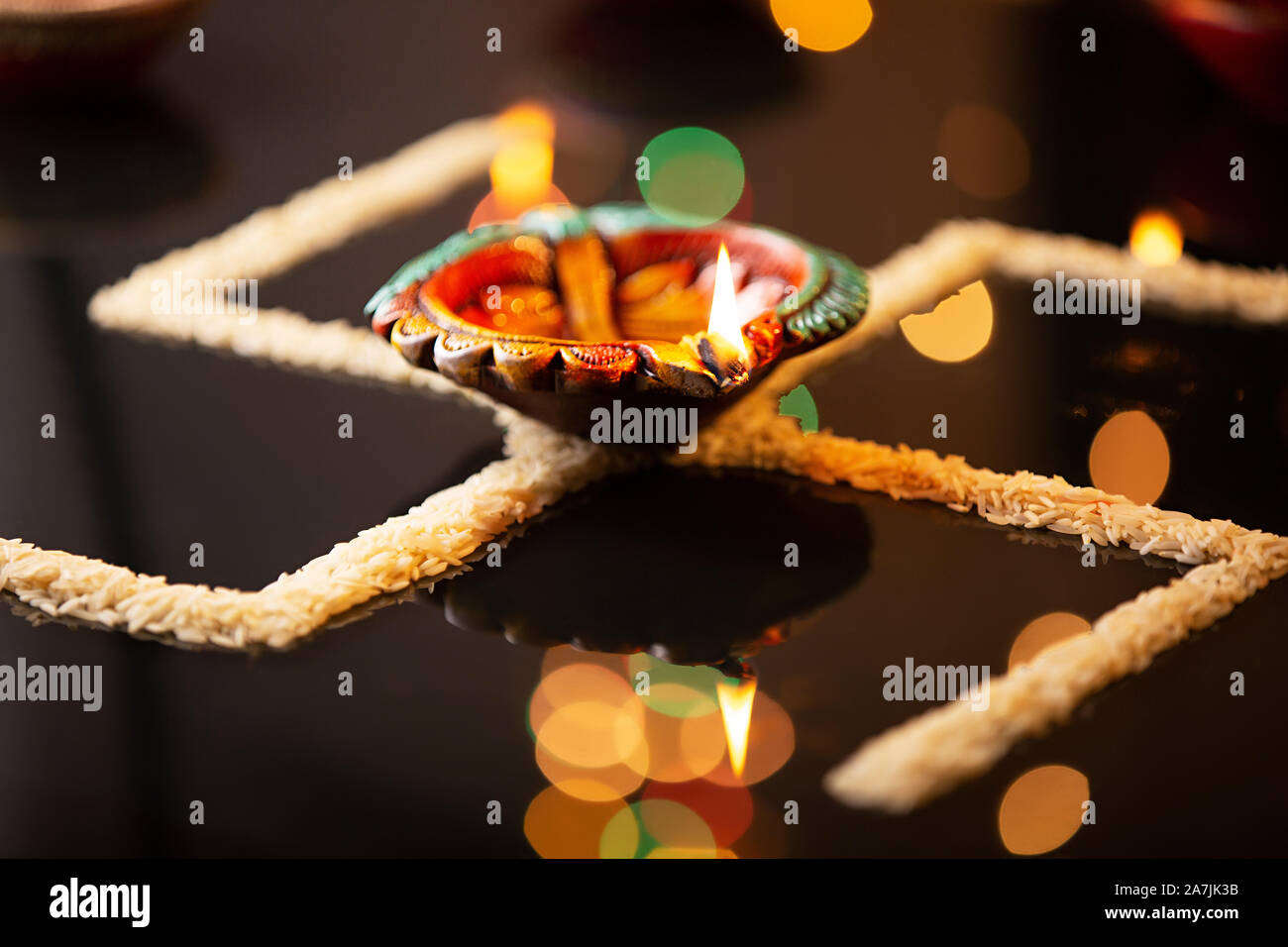 Burning diya oil-lamp Lighting With Rice arranged to-form swastik-symbol Durning Diwali Festival Celebration Stock Photo