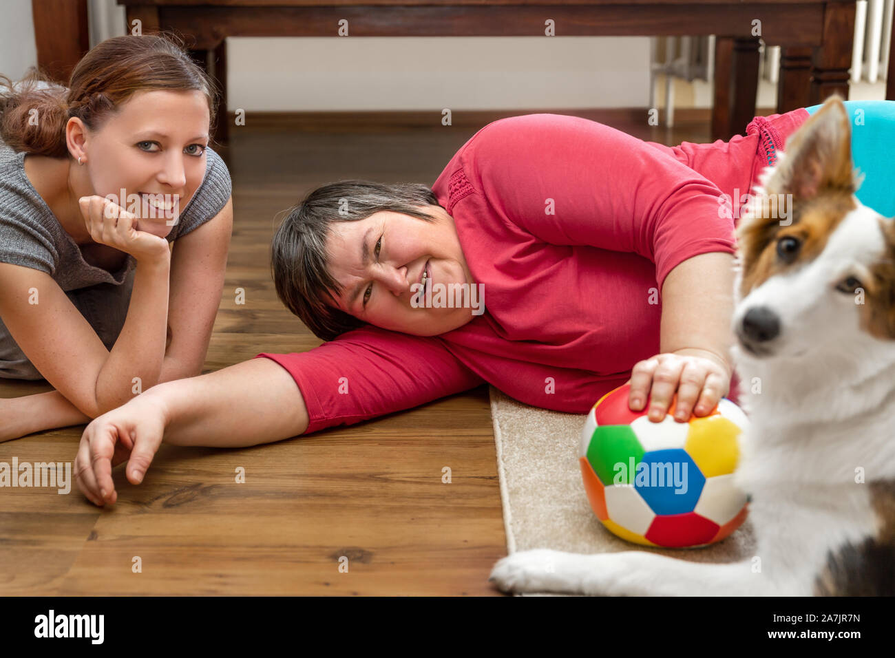 mentally disabled woman is laying on the floor, playing with a trained care dog Stock Photo