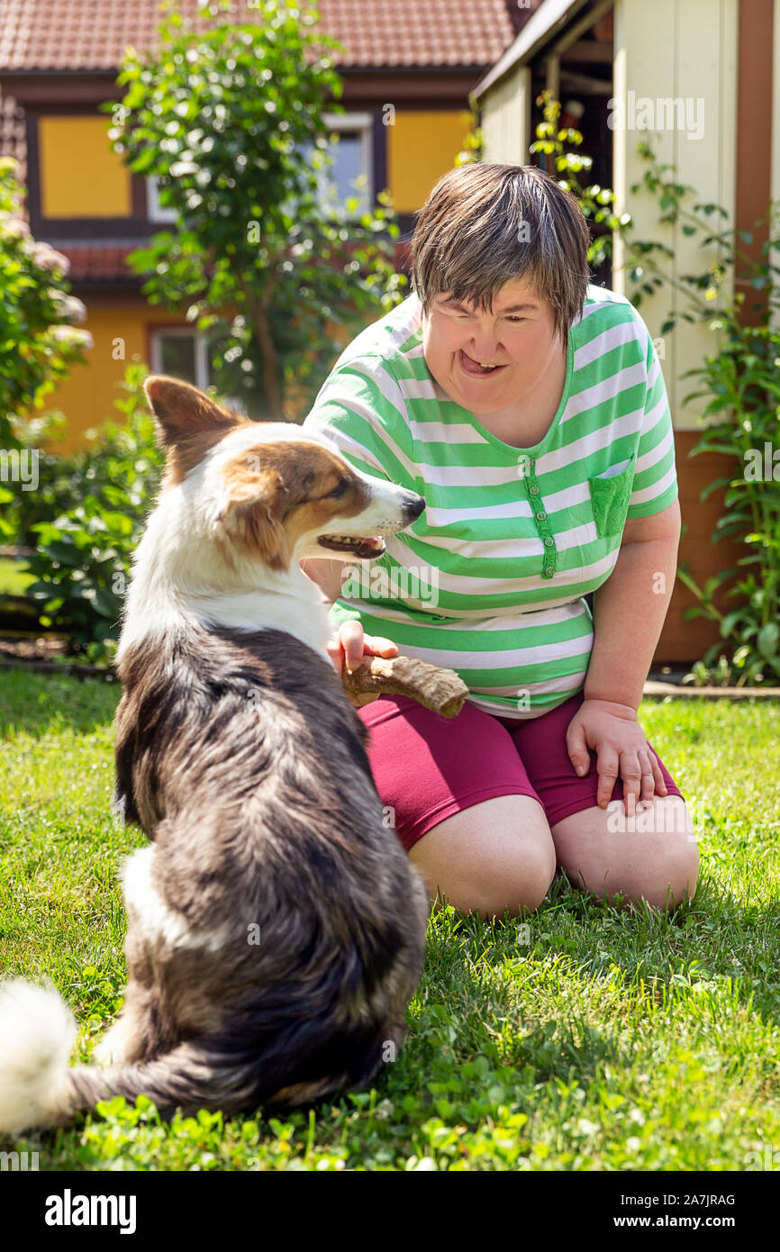 mentally disabled woman with a second woman and a companion dog, concept learning by animal assisted living Stock Photo