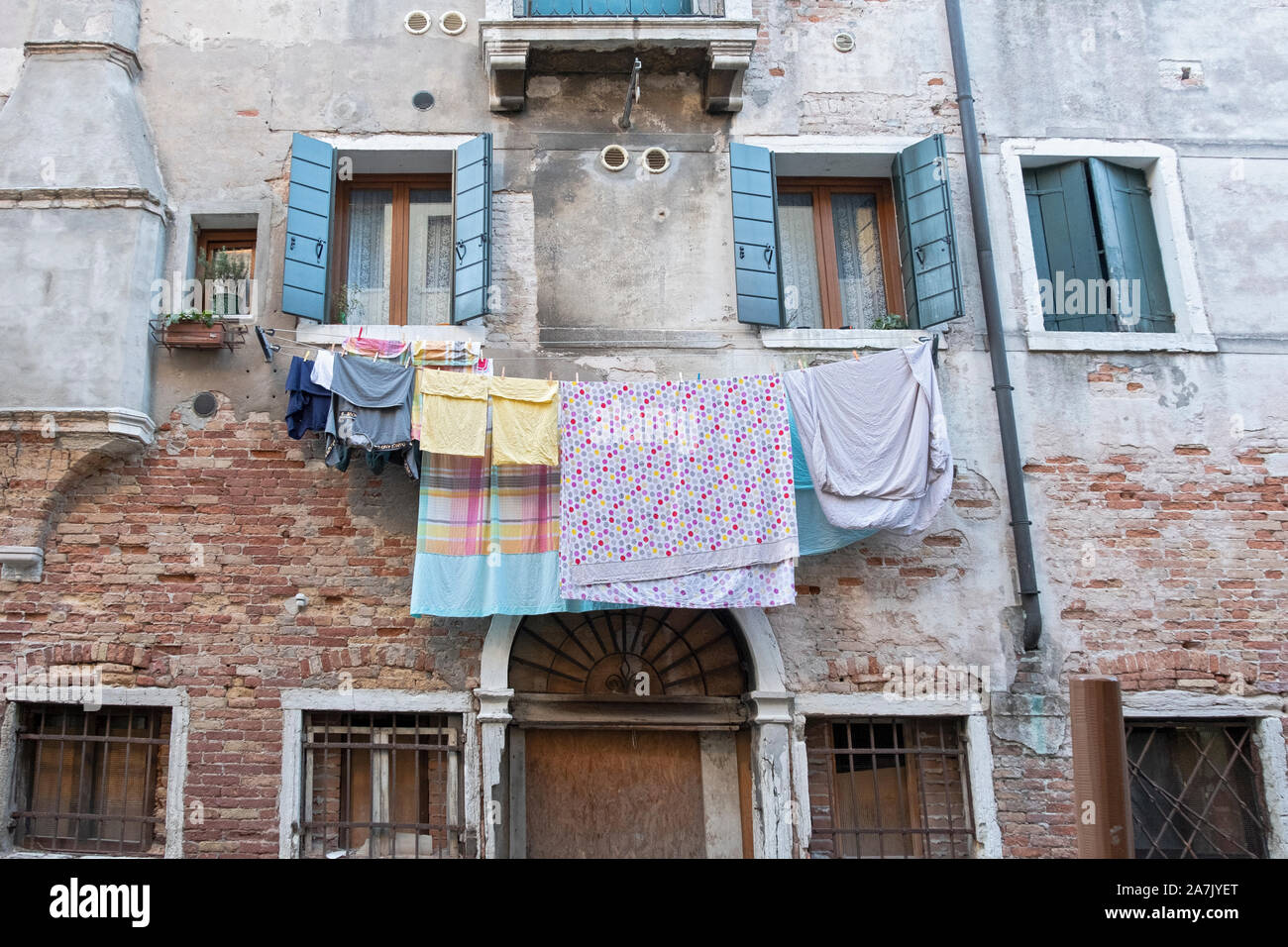 Laundry hanging to dry on the side of a 16th century building on a side street bordering a canal near Campo San Provolo Castello in Venice, Italy. Stock Photo