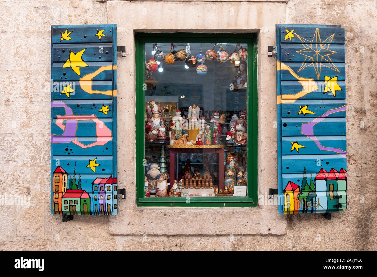 A gift shop window with ornate shutters in the old town section of Kotor Montenegro. On display is a section of Christmas ornaments. Stock Photo