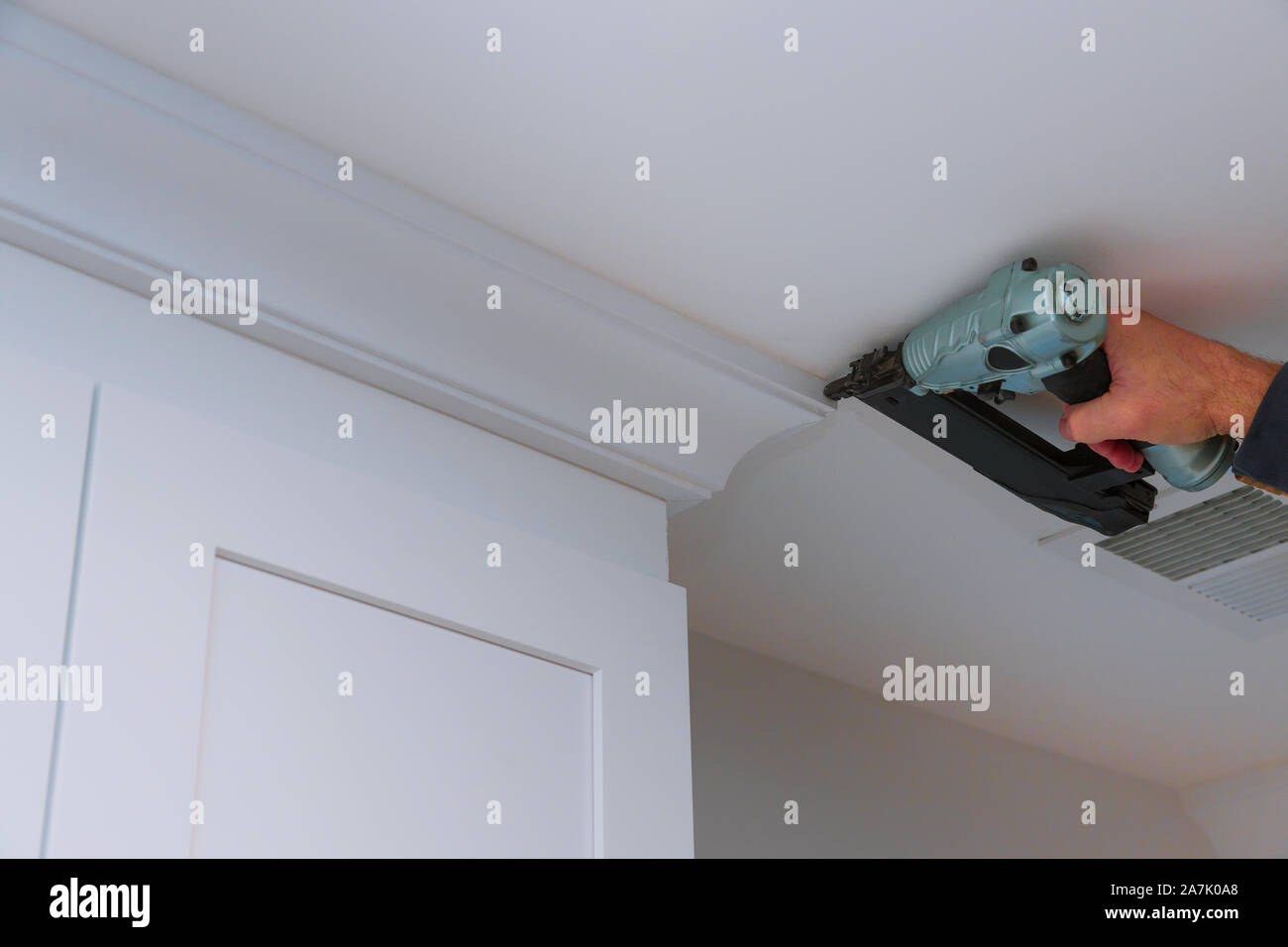 Carpenter nailing crown moldings in the kitchen framing trim