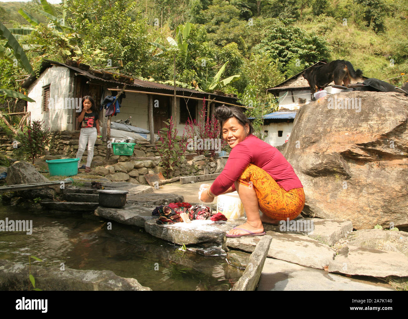 A Gurung woman washes clothes in a stream near her home, Sikles region, Nepal. Stock Photo