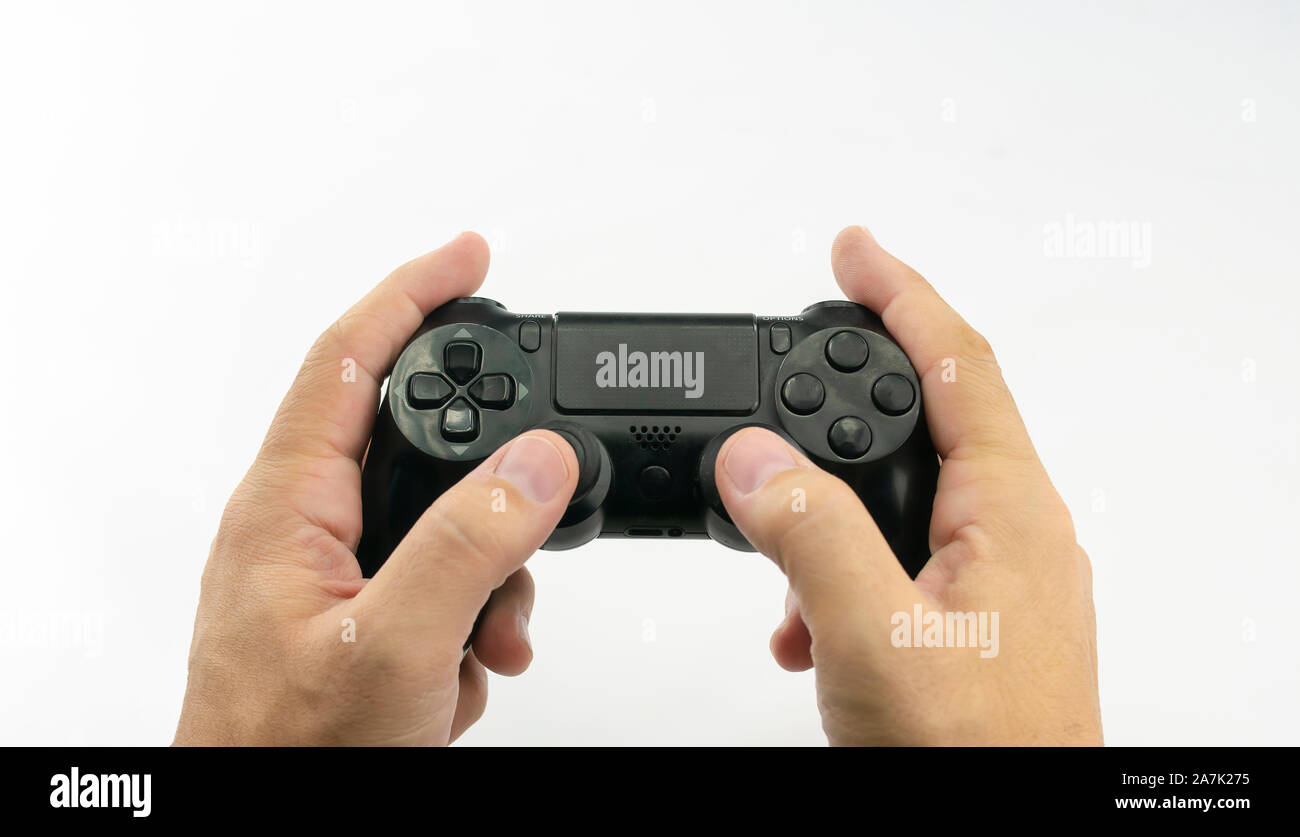 Video game console in black, with joysticks and buttons in the hands of a caucasian man on white background Stock Photo