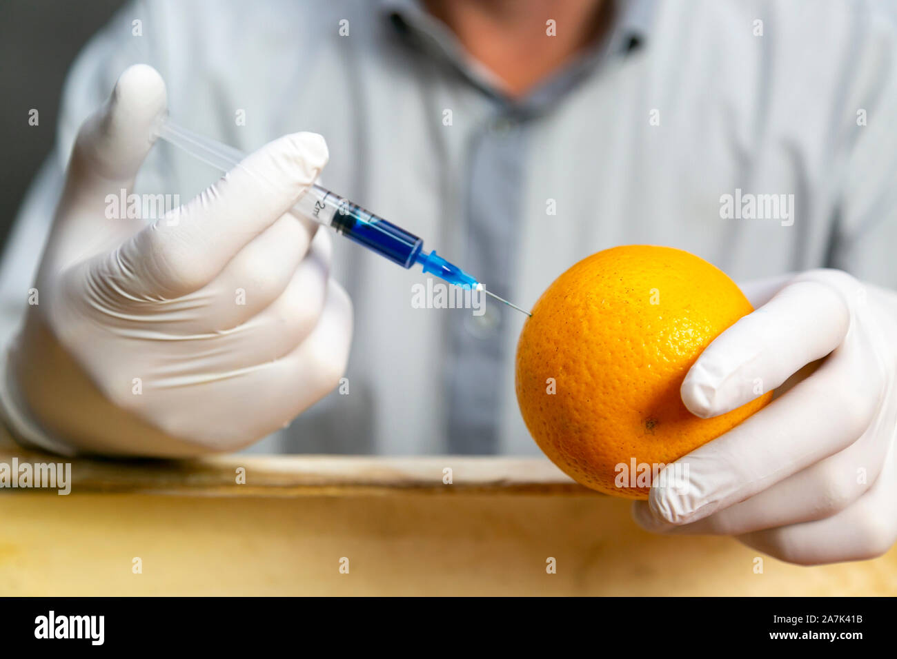 A man injects chemicals into an orange, pesticides and fertilizers and chemicals with a syringe to increase the shelf life of fruit Stock Photo