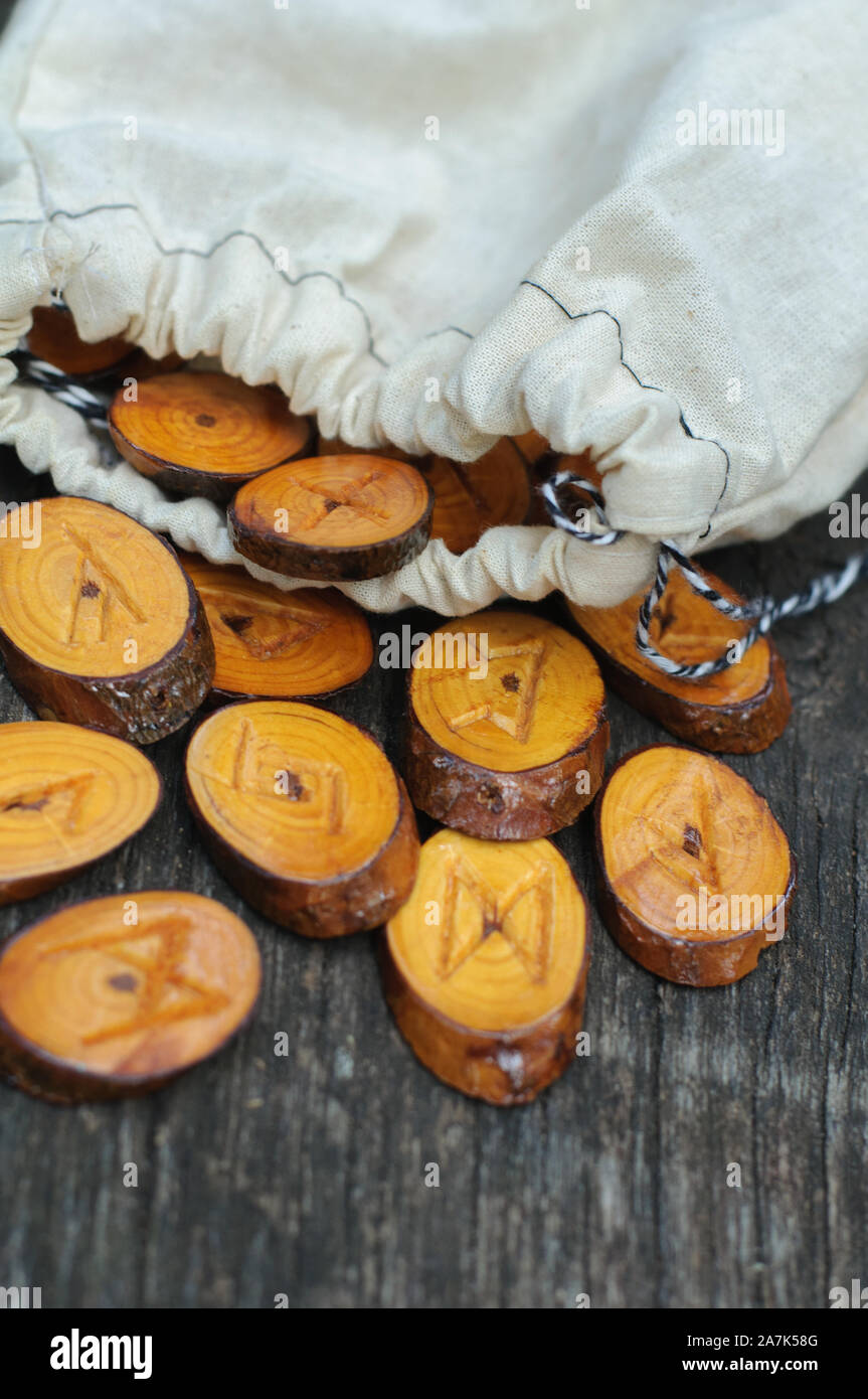 homemade wooden runes poured from a white pouch onto an old tree Stock ...